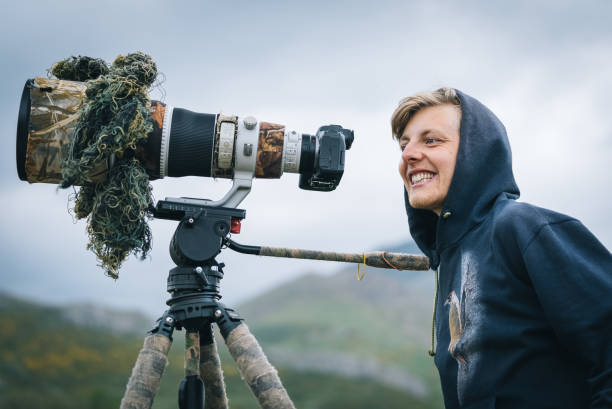 istock Young man with large lens camera on a tripod 1356750006