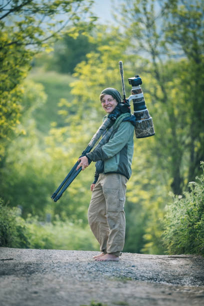 istock Young man with large lens camera and tripod 1356750010