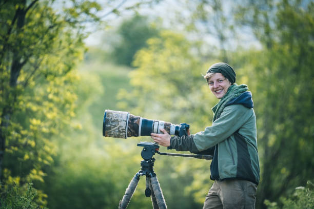 Young man with large lens camera and tripod