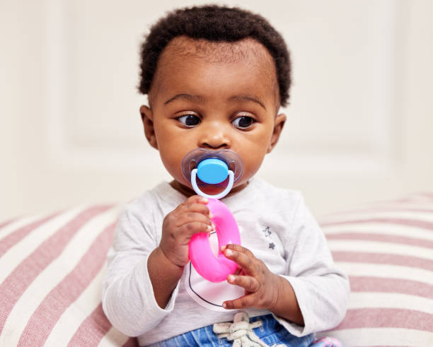 自分を楽しませるために彼女のおもちゃで遊んでいる小さな女の赤ちゃんのショット - newborn baby african ethnicity little girls ストックフォトと画像