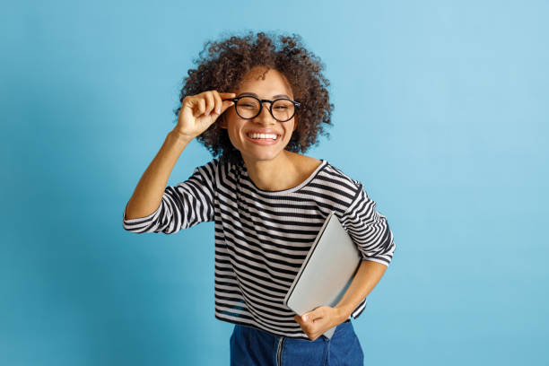 istock Cheerful woman with laptop adjusting her glasses 1356756024