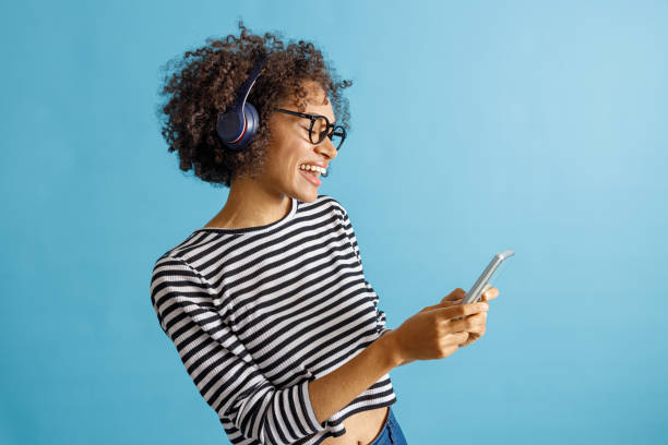 istock Joyful woman in headphones using mobile phone in studio 1356756042