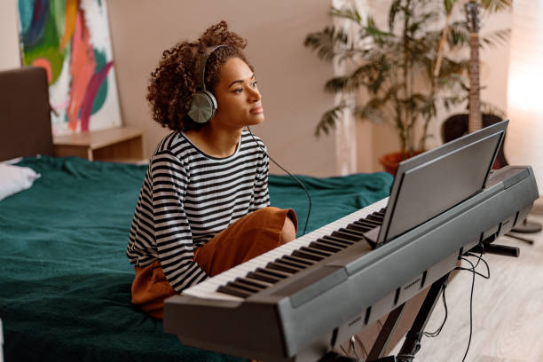 istock Multiracial woman is playing synthesizer at home 1356757250