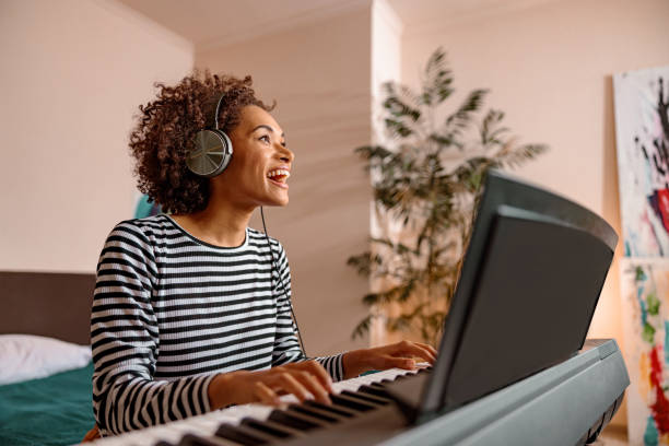 istock Cheerful young woman playing synthesizer at home 1356757268