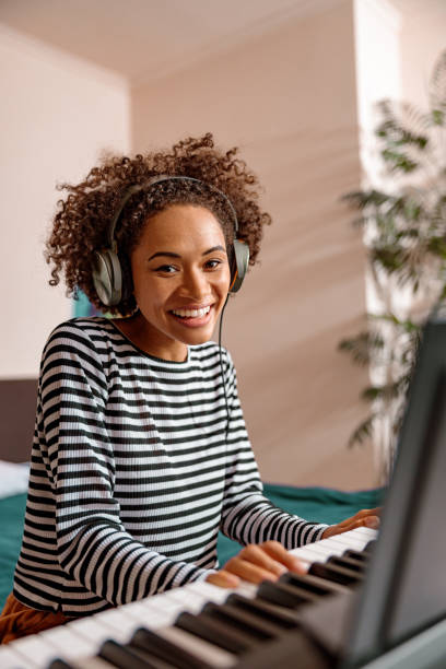 istock Cheerful multiracial woman playing synthesizer at home 1356757288