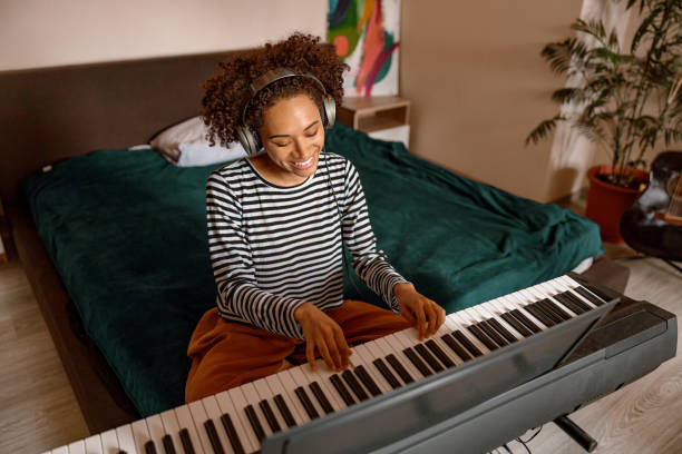 istock Joyful female musician playing synthesizer at home 1356757301