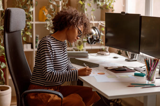 istock Multiracial young woman studying documents at home 1356757325