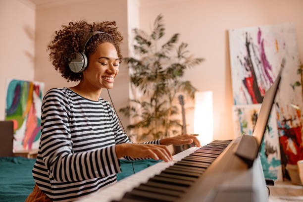 joyful young woman playing synthesizer at home - piano imagens e fotografias de stock