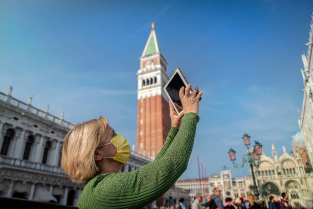 istock Senior Woman with Protective Mask Using Digital tablet in St. Mark's Square in Venice, Italy, during Pandemic 1356758315