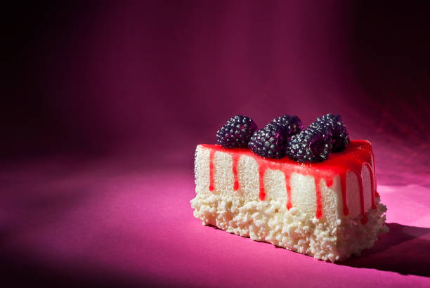 istock Cake with black raspberries on a pink background. Triangular piece of cake on a paper background. Sweets close up. 1356760107