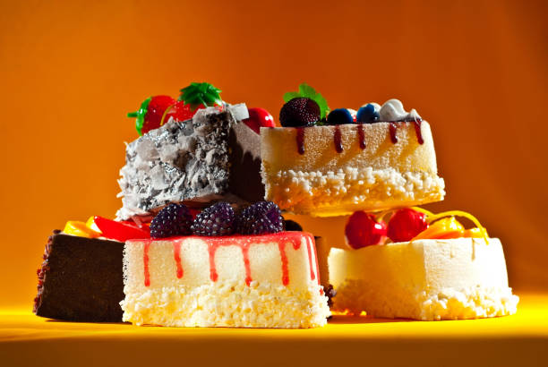 Various cakes on an orange background. Triangular pieces of cake on a paper background. Sweets on a pile close up.