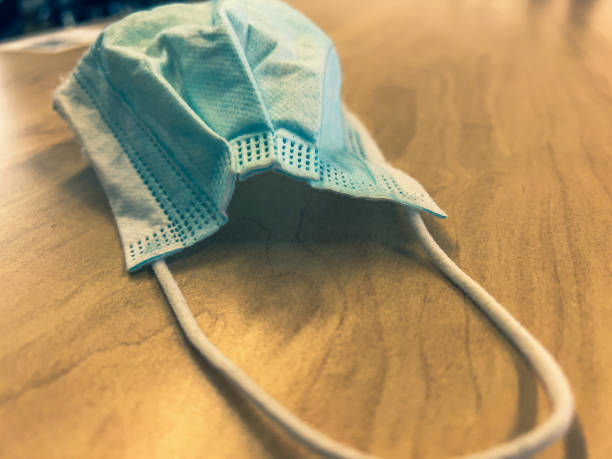 istock A surgical mask on a light wooden table. 1356761833