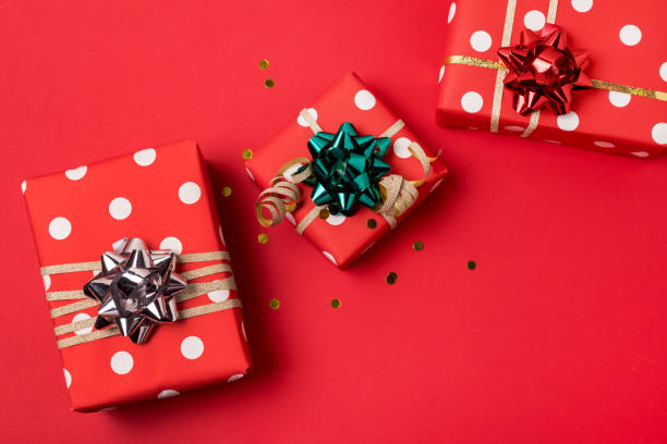 istock Three Gift Boxes for Christmas Holidays on Red Background Confetti Festive Background Horizontal 1356763841