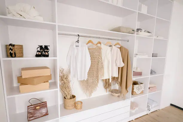 Photo of Female Fashionable Stylish Wardrobe. A Large White Built-in Wardrobe Stocked With Women's Clothing, Shoes and Accessories. Walk-in closet, Dressing Room for Women