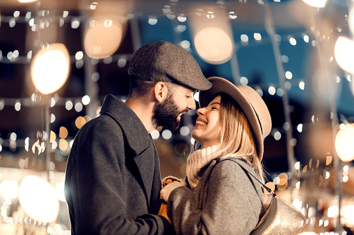 Amantes de la Navidad besándose al aire libre en la víspera de Año Nuevo. Una joven pareja feliz está parada en la calle rodeada de luces y besándose en la víspera de Año Nuevo. photo