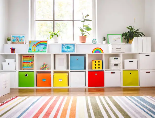 Photo of White nursery room with shelves and colourful boxes.