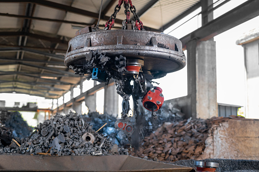 Close-up of scrap metal released into a metal shredder using industrial magnet at the recycling facility.