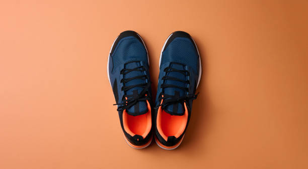 istock pair of blue textile sneakers on orange background, top view 1356773619