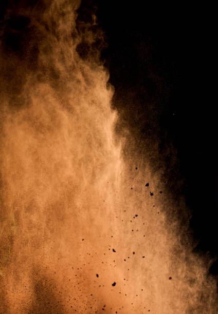 istock flying brown cocoa particles on a black background. Powder flies up 1356774366