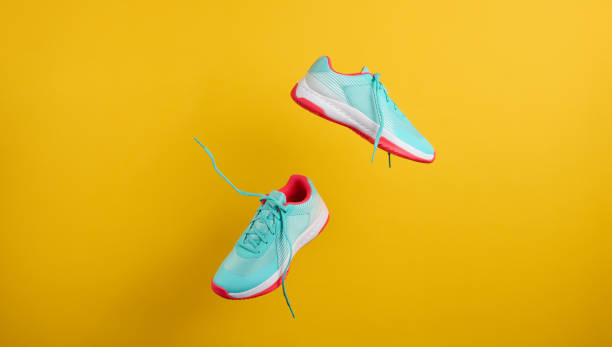 pair of textile blue sneakers with laces levitate on a yellow background. shoes for sports, jogging - pair imagens e fotografias de stock
