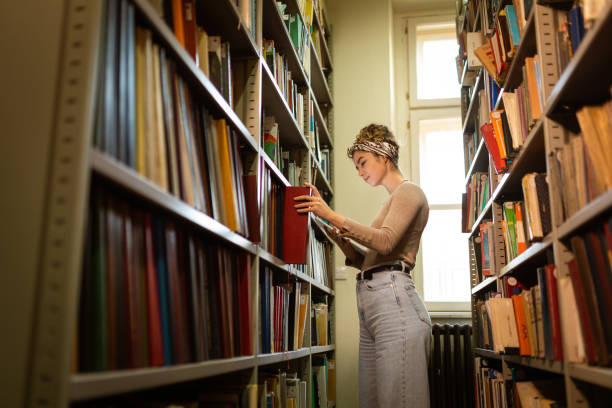 istock Young female student searching for book she need for exam 1356777660