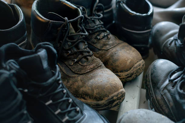 istock Many old work boots stand together. Old worn construction boots of workers. Real scene. Shift shoes 1356779320