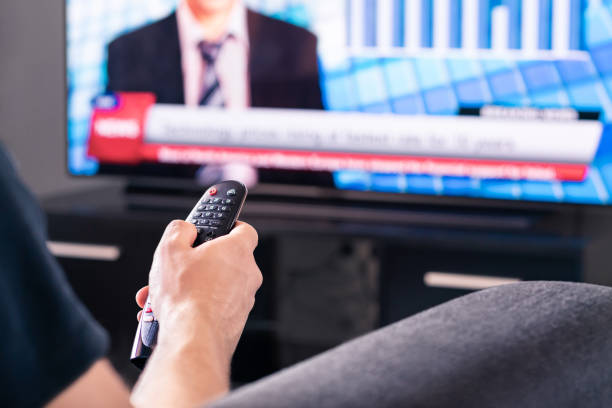 dernières nouvelles à la télévision. homme regardant un programme de diffusion télévisée en direct. covid19, coronavirus et informations médicales ou journaliste électoral et présentateur en politique mondiale. - newspaper headline technology color image photography photos et images de collection