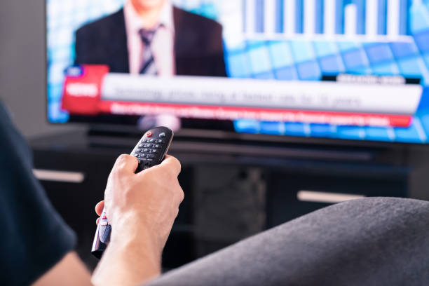 Breaking news on tv. Man watching live television broadcast program. Covid19, coronavirus and medical information or election reporter and presenter in world politics. stock photo