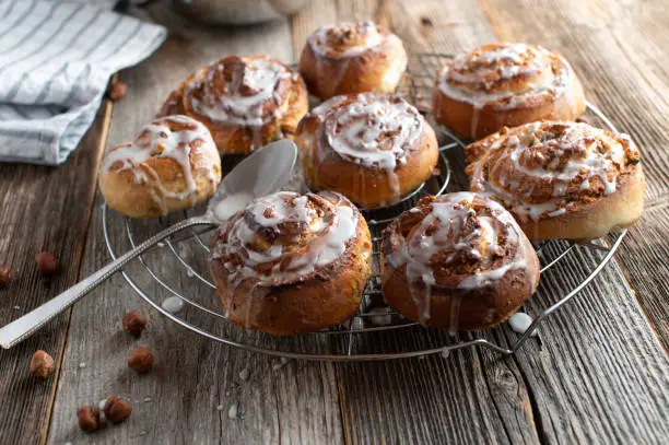 Traditional and homemade fresh baked cinnamon rolls with a delicious hazelnut filling. Served on a cooling rack on wooden table. Closeup and front view