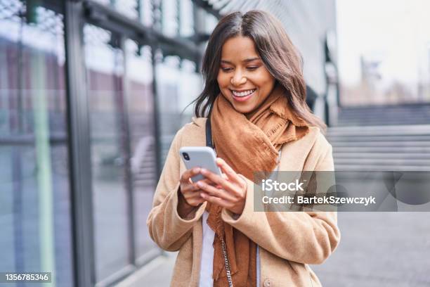 Woman In Coat Messaging On Smartphone Standing Outside In The City Stock Photo - Download Image Now