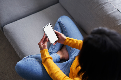 Overhead picture of black woman using smartphone, mobile phone on the sofa