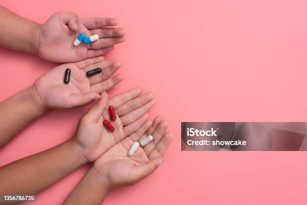 Kids Hands With Colorful Pharmaceutical Medicine Capsules On Pink Background Stock Photo - Download Image Now