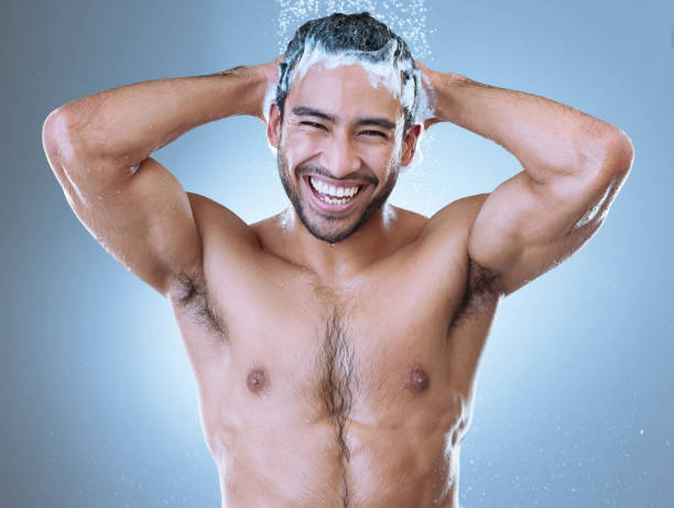 portrait d’un beau jeune homme profitant d’une douche sur fond gris - shower portrait male beauty chest photos et images de collection