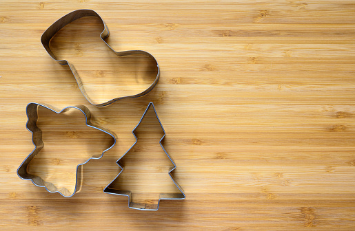 Christmas metal cookie cutters on a wooden background. Top view, focus on the form, free space on the right.