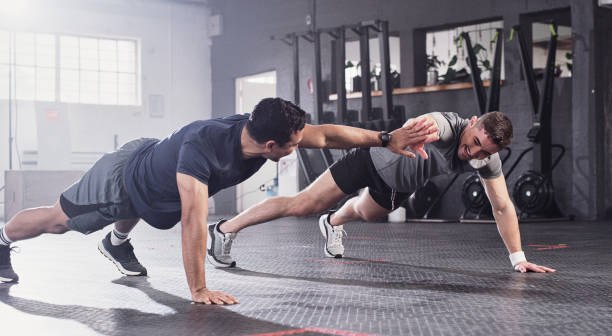 istock Shot of two men doing pushups sharing a high five at the gym 1356792004