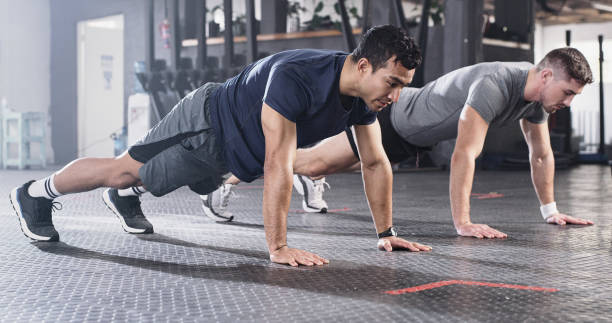 istock Shot of two focused men doing pushups at the gym 1356792006