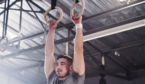 istock Shot of a young man lifting himself doing pull ups at a gym 1356792017