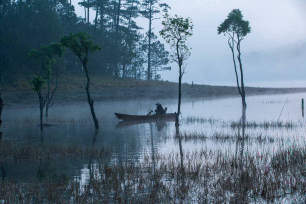 Fisherman in Tuyen Lam lake in a foggy morning, Da Lat city, Lam Dong province, central high lands Vietnam
