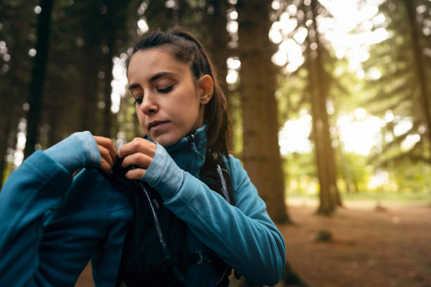 istock Young Caucasian woman, adjusting her backpack, during her hike in the forest 1356792238