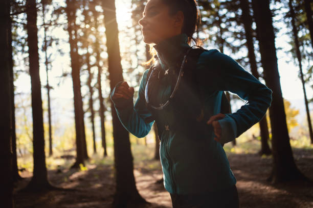 istock Active Caucasian young woman running in the forest during sunset 1356792542