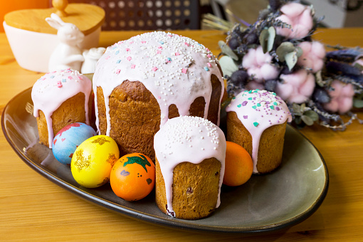 Traditional Easter cake with colored eggs on a platter on a wooden table.