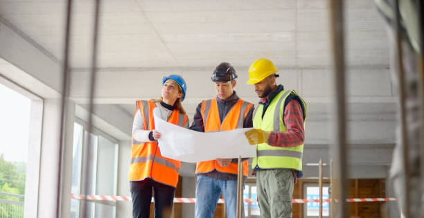 istock Foreman and forewoman discussing blueprint with architect 1356794957