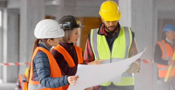 istock Foreman and forewoman discussing blueprint with architect 1356794982