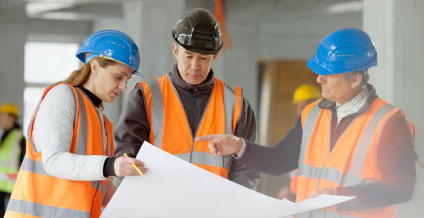 istock Foreman and forewoman discussing blueprint with architect 1356794993