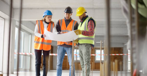 istock Foreman and forewoman discussing blueprint with architect 1356795007
