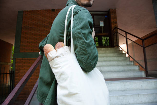istock Young man holding grocery bag with baguette bread 1356795507