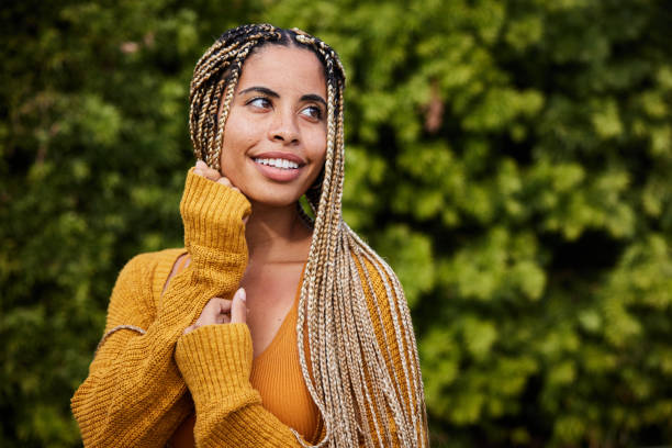 istock Young woman with braids in her glancing sideways outside and smiling 1356796871