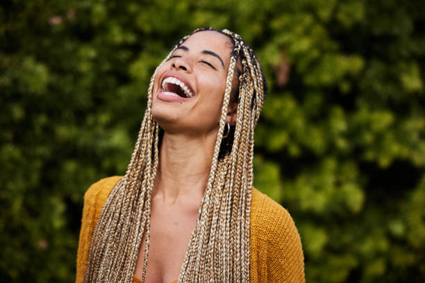 woman with long braided hair laughing with her eyes closed outside in summer - braided braids women long hair imagens e fotografias de stock