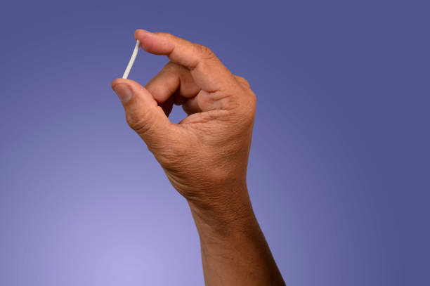main dans des gants en caoutchouc tenant un implant hormonal. - implant photos et images de collection