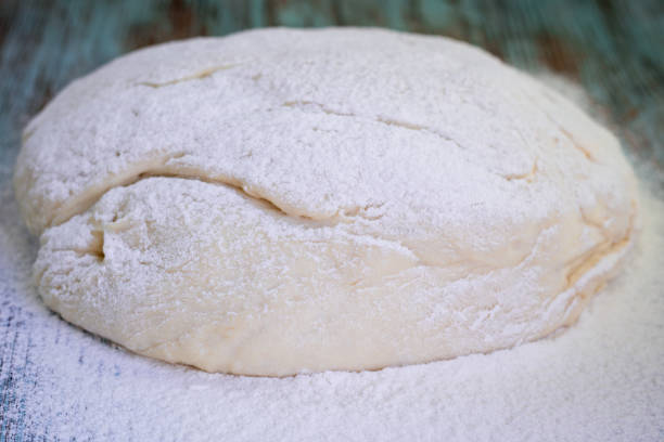 istock Fresh crude dough mixed and kneaded from white flour during baking 1356800291